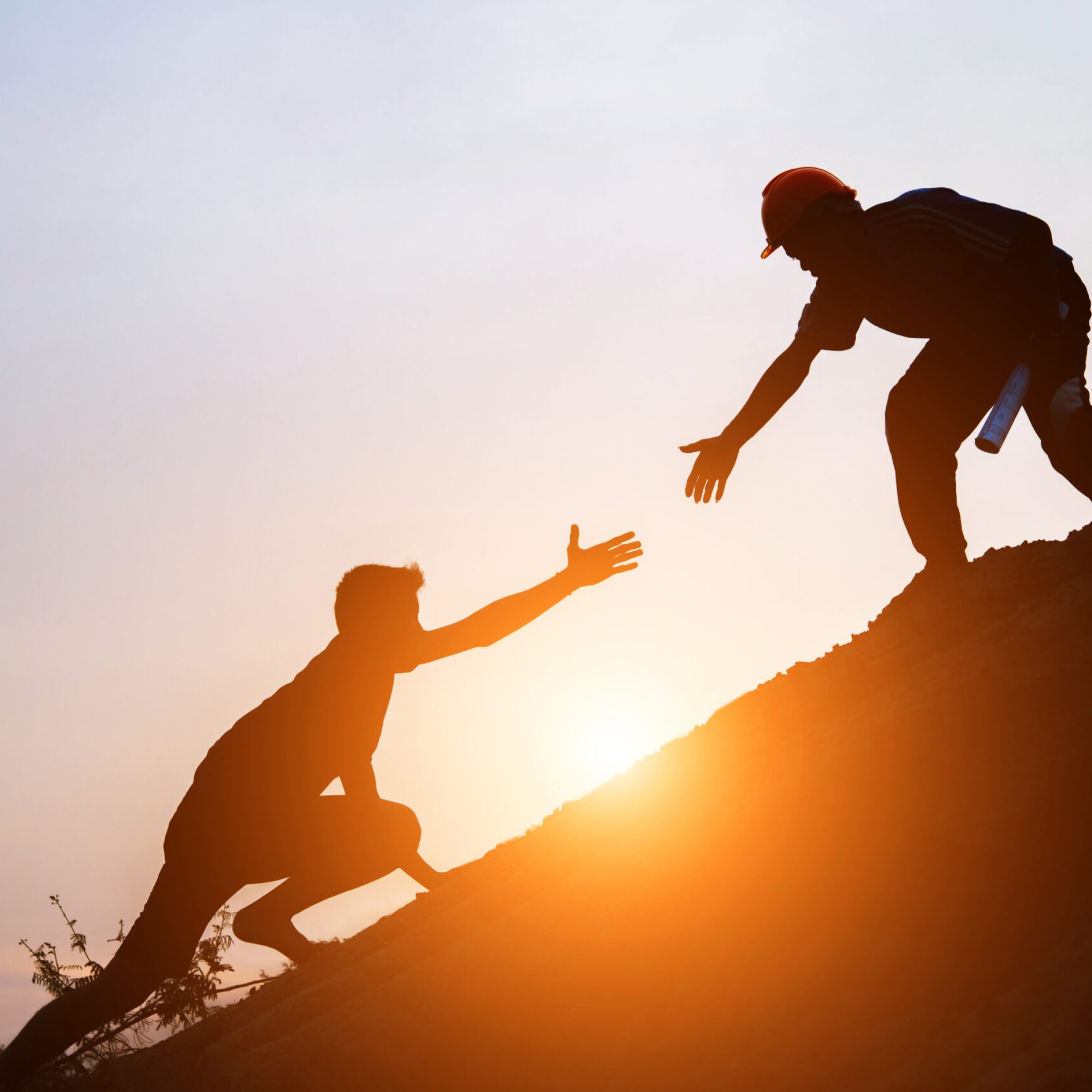 Tourists go up the hill in the sunrise to shake hands The male traveler shakes the hand of the male traveler who is climbing to the top of the hill